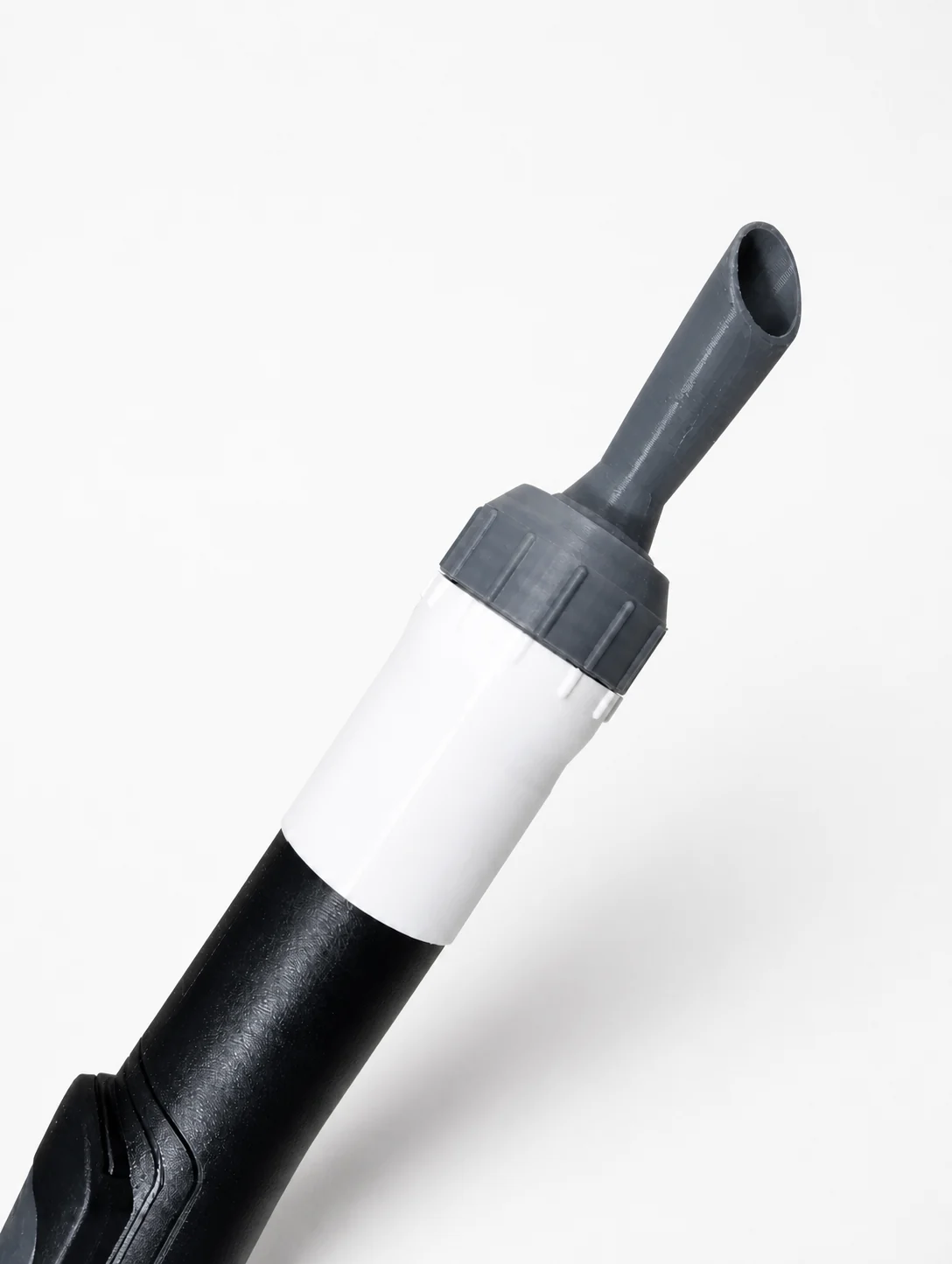Adaptateur gris et blanc imprimé en 3D installé au bout d'un tube d'aspirateur noir