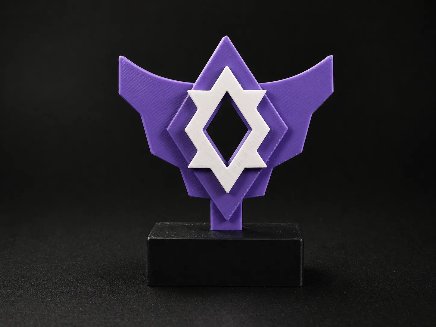 Emblème violet et blanc imprimé en 3D sur socle noir, exemple d'enseigne de comptoir