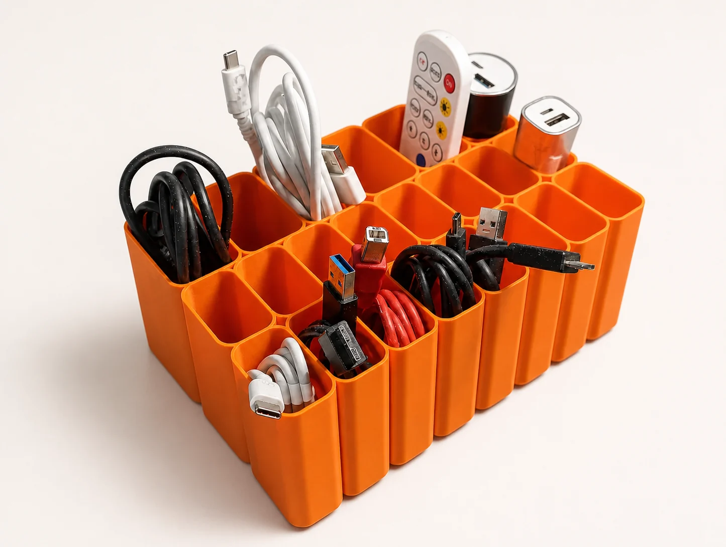 Organiseur orange imprimé en 3D avec compartiments pour câbles, adaptateurs et télécommandes